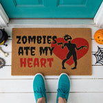 a door mat with a zombie graphic and the text "ZOMBIES Ate My Heart" printed on it.