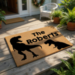 A black and white illustration of a T-Rex dinosaur on a textured surface, with the text "The Roberts" written above it.