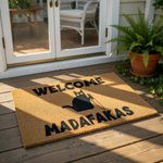 A black and white welcome mat with the text "WELCOME MADAFAKAS" printed on it.