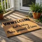 A welcome mat with the text "UNWELCOME Just kicking Make yourself at home" printed on it.