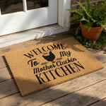 A wooden door mat with the text "Welcome To My Mother Cluckin Kitchen" printed on it.