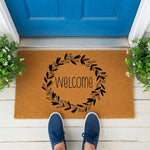 a welcome mat with a wreath and pumpkins
