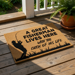 A door mat with a silhouette of a person fishing and the text "A GREAT FISHERMAN LIVES HERE WITH THE CATCH OF HIS LIFE" printed on it.