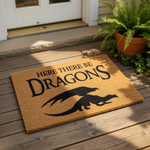 A textured area rug with a dragon silhouette and the text "HERE THERE BE DRAGONS" printed on it.