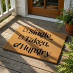 a door mat with the text "Single, Taken, Hungry" printed on it, along with a pumpkin decoration and some other fall-themed items.