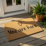A beige doormat with the text "You are here" printed on it.