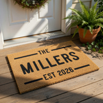 A beige doormat with the text "THE MILLERS EST 2021" printed on it.