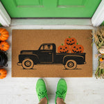 a door mat with a truck with pumpkins on it