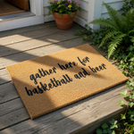 A textured doormat with the phrase "gather here for basketball and beer" printed on it.