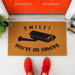 a door mat that says smile you're on camera
