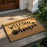 A welcome mat with the text "WELCOME home" printed on it, along with a pumpkin and leaves.