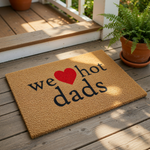 A textured doormat with the phrase "we hot dads" printed on it, along with a red heart symbol.