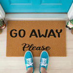 A textured doormat with the words "Go Away Please" printed on it, along with a pair of feet positioned in front of it.