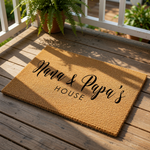 A textured, beige-colored doormat with the text "Nana & Papa's HOUSE" printed on it.