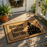 A welcome mat with the text "Welcome Foolish Mortals" and a silhouette of a castle-like building.