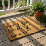 A textured area rug with the phrase "Home Sweet Home" printed on it, along with a small circular logo that reads "WOOD BY STU - EST. 2010".