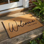 A textured, beige-colored welcome mat with the text "Welcome" and "The Curtis" printed on it.