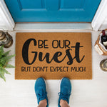 a door mat that says be our guest but don't expect much