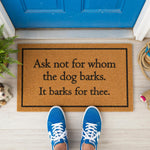 A wooden door mat with a humorous message that reads "Ask not for whom the dog barks, It barks for thee."