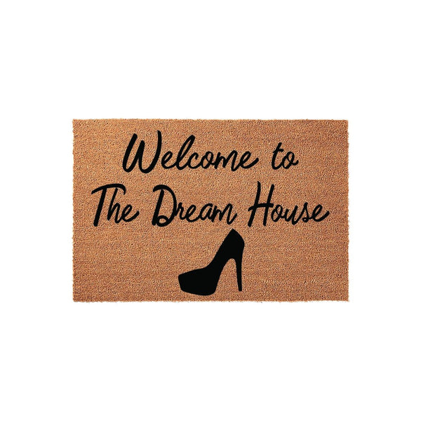 a textured area rug with the text "Welcome to The Dream House" printed on it, along with a silhouette of a high-heeled shoe.