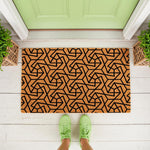 Geometric pattern coir doormat featuring a modern black line design on natural fiber, perfect as a stylish outdoor welcome mat for your front porch entrance, shown on a white deck with green shoes and potted plants nearby.