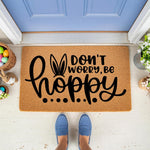 Easter bunny doormat with Don't Worry Be Hoppy text and rabbit ears design, a natural coir fiber welcome mat for spring porch decor, featuring a festive holiday message for your front door entrance and seasonal home entryway.