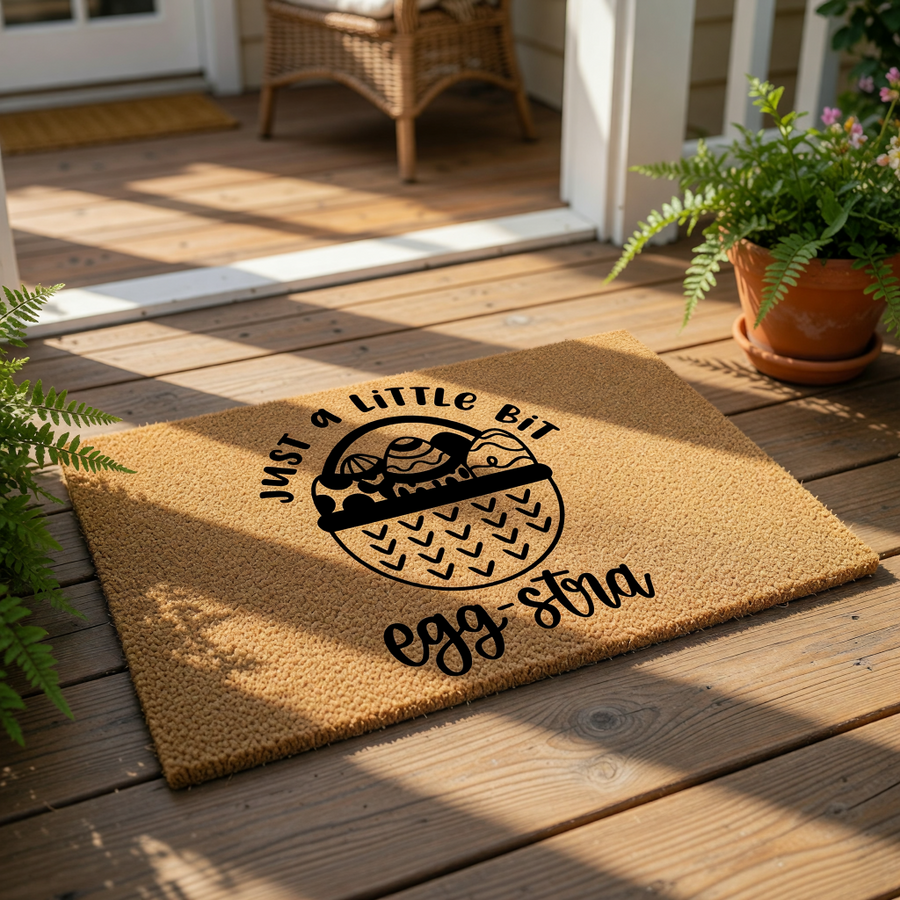 Easter egg doormat featuring a basket design and the text Just a Little Bit Egg-stra, this natural coir welcome mat is a festive spring porch decor piece for your front door entry, adding a fun seasonal touch to your home