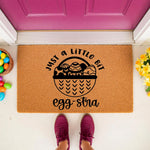 Easter egg doormat with a natural coir fiber texture, featuring a basket design and the punny phrase Just a Little Bit Egg-stra, perfect for spring porch decor, front door entryways, and seasonal home welcome mat floor coverings.