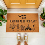 Plant lover welcome doormat with funny text Yes I Really Need All Of These Plants and cute potted plant illustrations, featuring a natural coir fiber texture for a front porch entry rug that makes a fun housewarming gift for