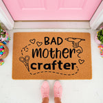 Bad Mother Crafter doormat for DIY lovers, featuring a funny quote with glue gun and scissors icons on a natural coir welcome mat, placed at a pink front door entrance for a creative home decor look that crafters will love.