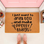 Craft room doormat with text I just want to drink tea and make pretty things, featuring scissors and paintbrush icons on a natural coir welcome mat for artists, crafters, and hobbyists placed at a front door entrance for home