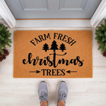 Farm Fresh Christmas Trees doormat featuring black text and pine tree icons on a natural coir welcome mat, displayed on a porch floor with festive greenery for a holiday home decor look that greets guests at the front door