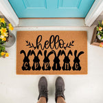 Hello Spring bunny doormat featuring black rabbit silhouettes and seasonal text on a natural coir welcome mat, placed on a porch for outdoor home decor that adds a festive touch to your entryway during the spring holiday season.