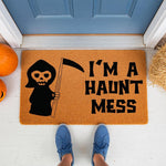 Funny Halloween doormat featuring a cute grim reaper illustration and the text I am a haunt mess, this natural coir welcome mat is a spooky front porch decor piece for fall home entryways and seasonal outdoor floor mats.