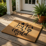 Joy to the World Christmas doormat made of natural coir fiber with black ink text and festive star and snowflake designs, perfect for a holiday front porch welcome mat or seasonal home decor for your entryway floor.