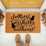 Funny Christmas doormat featuring the text Jolliest Bunch of Assholes This Side of the Nuthouse, a natural coir welcome mat for front porch decor that adds humorous holiday personality to your home entrance with festive tree