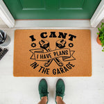 Garage themed doormat for mechanics featuring crossed wrenches and the text I cant I have plans in the garage, this natural fiber welcome mat is a funny front porch decor piece for any handyman or car enthusiast home entrance.