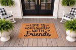 Life is much sweeter with friends coir doormat featuring black script text on a natural fiber welcome mat, displayed on a front porch with rocking chairs and potted ferns for a stylish home entrance and outdoor decor entryway