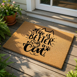 Cat lover doormat with Life is Better with a Cat text printed in black on a natural coir fiber welcome mat, featuring cute feline ears and paw print graphics for a fun entryway decor piece for any pet owner home entrance.