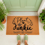 Plant Junkie coir doormat for front porch entryways, featuring a natural fiber welcome mat with black botanical text and floral illustrations, perfect for housewarming gifts for plant lovers and indoor garden decor enthusiasts.