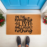 Funny Christmas doormat with the text On The Naughty List And I Regret Nothing, featuring a natural coir fiber welcome mat placed on a porch floor in front of a blue door with holiday decor and a person wearing gray sneakers