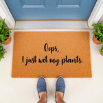 Funny plant lover doormat with the text Oops I just wet my plants, a natural coir welcome mat for front porch decor that makes a humorous housewarming gift for gardeners and plant parents who love indoor and outdoor greenery.