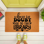 When in Doubt Go to the Library doormat featuring black typography on a natural coir welcome mat, placed on a porch with books and sneakers, perfect for a book lover home decor entrance or a unique housewarming gift for readers.
