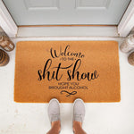 Funny welcome doormat for front porch with text reading Welcome to the shit show hope you brought alcohol, featuring a natural coir fiber texture and black script lettering for a humorous home entryway decor piece that greets