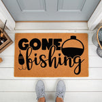Gone Fishing coir doormat for front porch, featuring a black printed bobber and hook design on natural fiber, perfect for a fisherman home entrance or outdoor welcome mat decor on a white wood floor with a person standing in gray