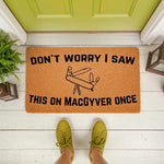 Funny doormat with a multi-tool illustration and text about a classic action show, featuring a natural coir welcome mat on a porch floor that makes a great housewarming gift for fans of DIY, home repair, and clever humor.