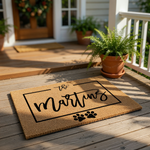 Personalized family name coir doormat featuring a rectangular border, script text, and cute dog paw prints, making this custom outdoor welcome mat a durable and stylish housewarming gift for any pet lover home entrance.