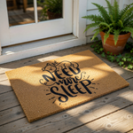 Need More Sleep cat doormat on a porch, featuring a natural coir welcome mat with a sleeping kitten illustration and funny typography, perfect for a front door entrance or as a humorous housewarming decor piece for cat lovers.