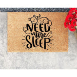 Cat lover doormat with a sleeping kitten design and the text Need More Sleep, this natural coir fiber welcome mat is a funny front porch rug for cat owners who enjoy home decor with a humorous and cozy feline theme.