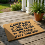 Couples board game doormat with a natural coir texture, featuring black text that reads Couples That Play Board Games Together Stay Together with dice icons, perfect for a gamer home entrance or a fun housewarming welcome mat.